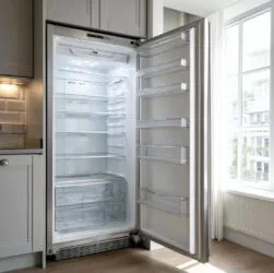 an open, freshly cleaned, empty refrigerator in a modern London apartment kitchen